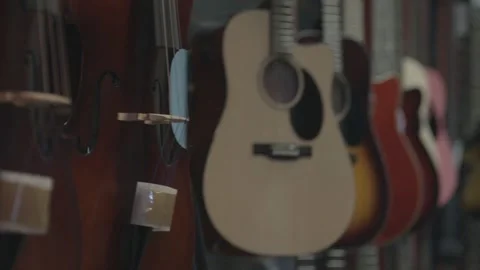 Rack focus shot from a close guitar to several on a back wall Stock Footage 255298052