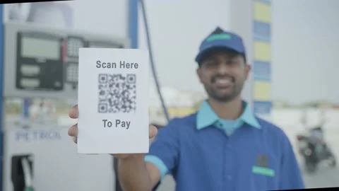 Rack focus shot of petrol pump worker showing scan here to pay qr code for payme Stock Footage 173462579