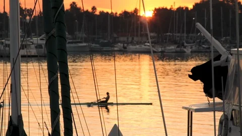 Rack focus shot of rower passing through marina at sunrise Stock Footage 87817065