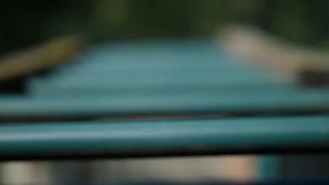 Rack focus slow with breathing across monkey bars to trees in garden outdoors Video stock 95032761