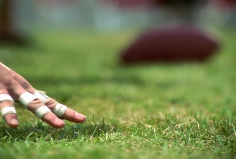 Rack-focus of slow-motion hands on scrimmage line and football being tilted Stock Footage 86918561