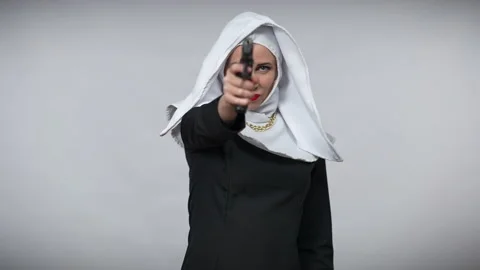 Rack focus from smiling woman in nun costume to handgun stretched at camera and Stock Footage