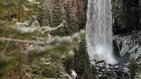 Rack focus from snow covered branch to powerful waterfall Video stock 83232529