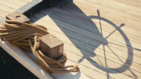 Rack Focus from Steering Wheel Shadow to Nautical Ropes on Wooden Deck Stock Footage 341324614
