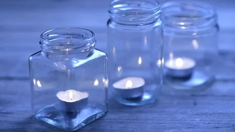 Rack focus on three lit candles in glass jars. White balance for candles. Stock Footage 71537922