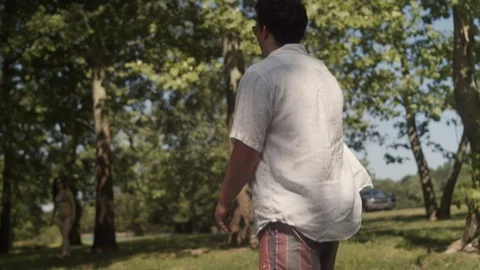 Rack focus of two friends tossing a frisbee in a forest near a lake Stock Footage 116773242