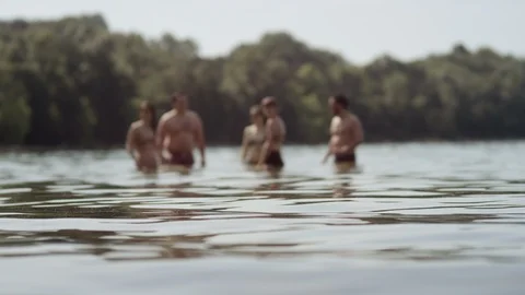 Rack focus wide shot of five young friends cooling off in waist high lake water Video stock 116749061
