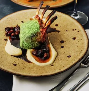 Rack of lamb in breaded pistachio nuts, dark sauce and herbs Stock Photos