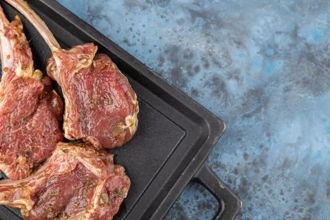 Rack of lamb marinated on the bone lies on a stone black board Stock Photos