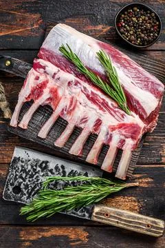Rack of lamb raw meat with bone on a cutting board. Dark wooden background. Top Stock Photos