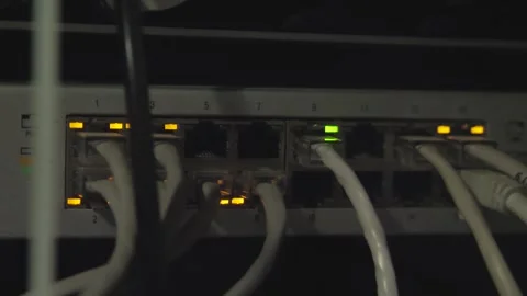 A rack-mounted network switch in a dimly lit room with Ethernet cables Stock Footage 274826676