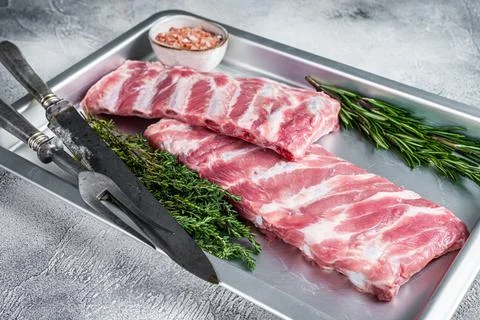 Rack of Raw pork spare ribs in kitchen oven tray with herbs. White background Stock Photos