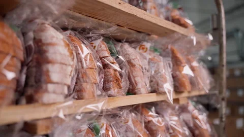 Rack with ready packed fresh bread close-up. Bread factory indoors Stock Footage 250263956