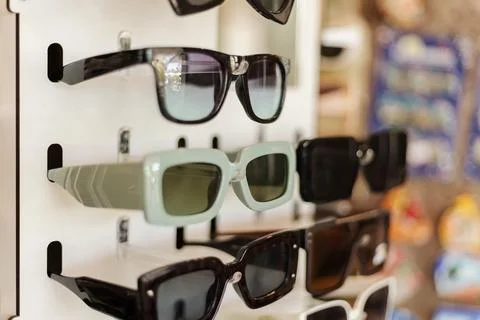 A rack shows different styles of sunglasses in a retail store. Each pair has  Stock Photos
