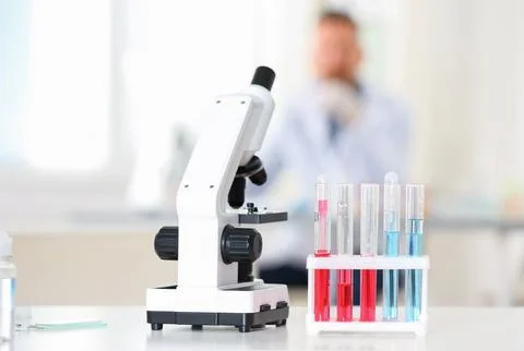 Rack with test tubes and microscope on table in laboratory. Research and anal Stock Photos