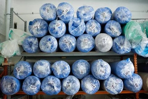 On the rack there are rolled sheets of blue foam rubber, packed in film Stock Photos
