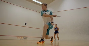 A Racketball Instructor shows his client a backhand winning shot. Video stock 85532375