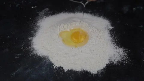 Racking an egg into flour to make bread Stock Footage 154984949