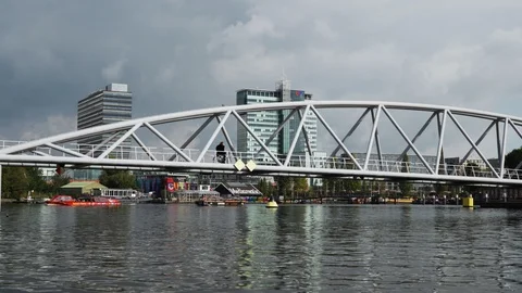 Racking shot on River Amstel in Amsterdam with cyclist crossing bridge. Stock Footage 87875022
