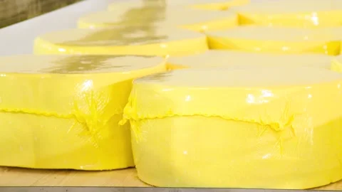 Racks filled with numerous round wheels of yellow cheese. Видео 339766195