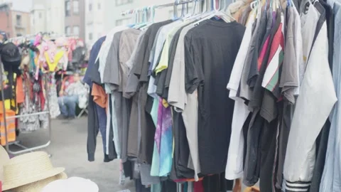 Racks of hanging vintage second hand thrift consignment clothes at a street Stock Footage 243811429