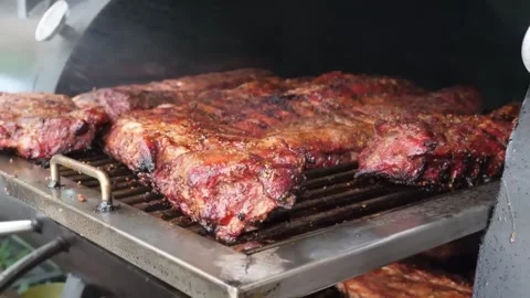 Racks of Smoked Beef Ribs Cooking on a Professional Barbecue Grill Stock Footage 338212403