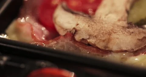 A raclette dish is cooked and boiled on the table in a bowl. macro Stock Footage 179026308