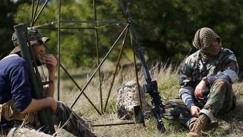 Radar base. Two armed Afghan soldiers are talking. One of them has a MANPADS Stock Footage 127932321