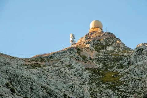 Radar dome station and radio antennas on top of a mountain at sunset Stock Photos