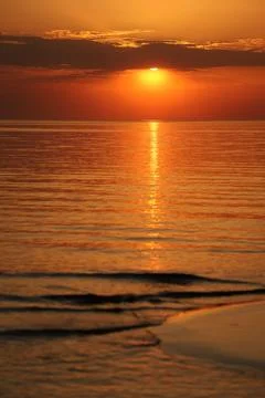 Radiant evening sun setting over a peaceful sea beach, creating a bright yellow Stock Photos
