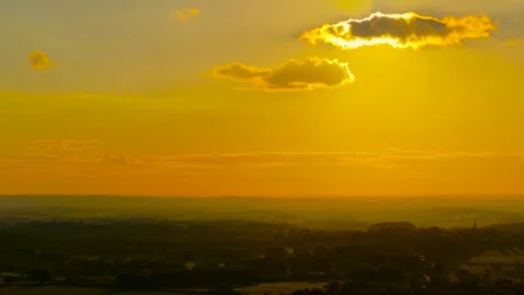 Radiant sun descending through clouds above rural landscape. Soft light coloring Stock Footage 328357611