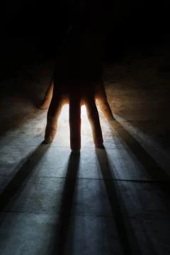 Radiates Rays of Light shine through silhouette of hand in black Stock-Fotos