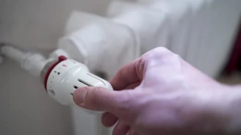 Radiator handle. A man manually adjusts the temperature on a heating radiator Video stock 235988374