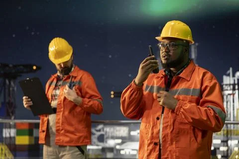 Radio operator working on drilling derrick on ocean using walkie talkie Stock Photos