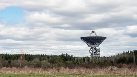 A radio telescope above forest in front of coudy sky 動画素材 154396752