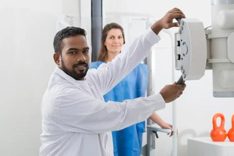 Radiologist Adjusting X-ray Machine Over Patient In Hospital Stock Photos