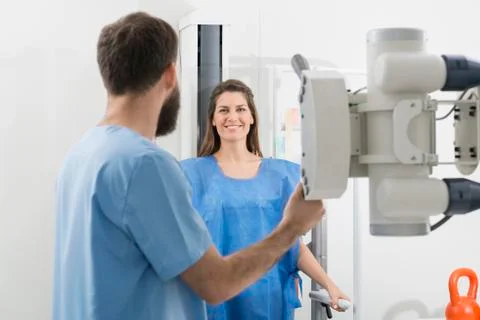 Radiologist Adjusting X-ray Machine On Female Patient At Hospita Stockfoto's