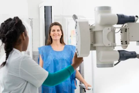 Radiologist Adjusting X-ray Machine On Female Patient At Hospita 写真素材