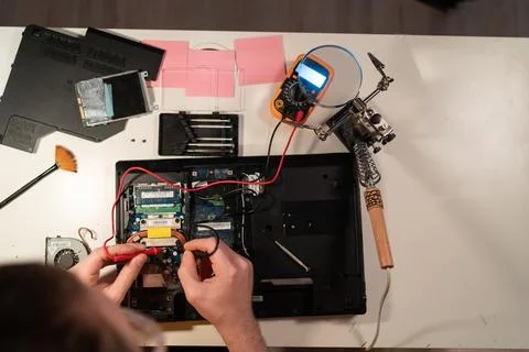 Radioman testing electric current in circuit board of disassembled laptop usi Stock Photos