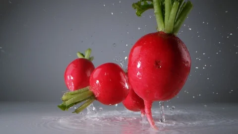 Radishes falling on water surface. Slow Motion. Stock Footage 128771296