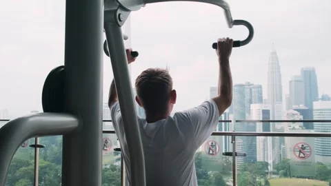 Raer view of man exercising on chest press fitness machine in outdoor gym on Stock Footage 280983759