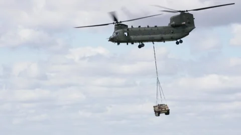 RAF Chinnok flying while lifting an armoured personnel carrier 스톡 동영상 276337023
