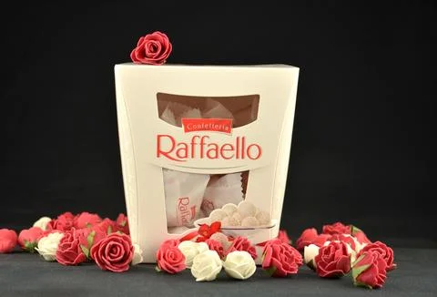 RAFFAELLO candy box with small white and red roses lying around Stock Photos