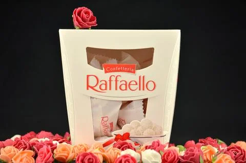 RAFFAELLO candy box with small white, red and orange roses Stock Photos