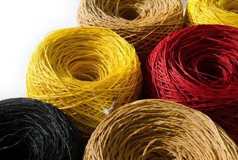 Raffia rolls close-up. Skeins of multi-colored raffia on a white background. Stock Photos
