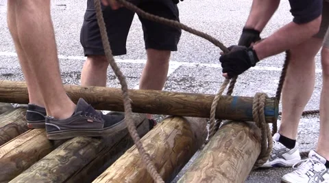 Raft Competition - Team pulling rope and fasten trunks building a Raft Video stock 64300938