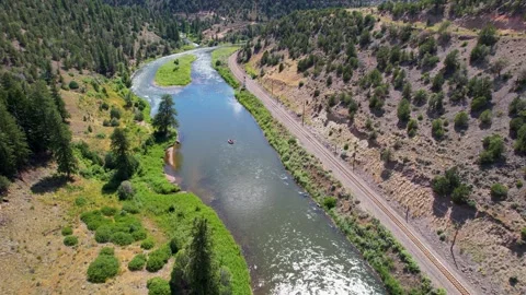 Raft floating down Colorado river with mountains in background Video stock 256619918