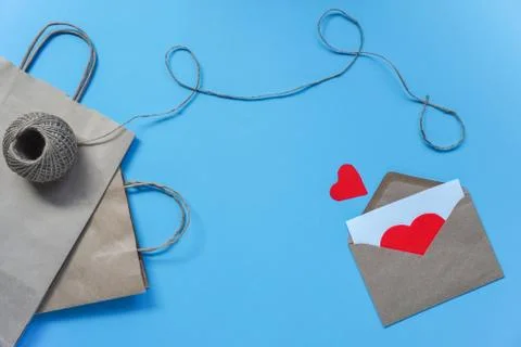 Raft paper bag with string and envelope with white sheet and red hearts on bl Stock Photos