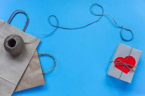 Raft paper bag with string and envelope with red heart on box on blue backgro Stock Photos