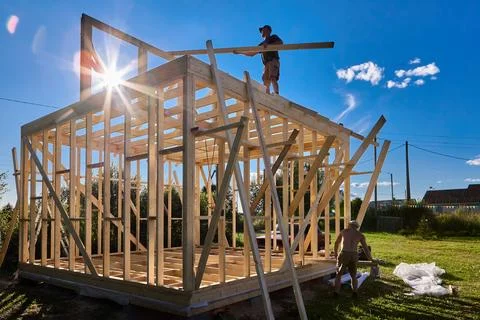 Rafter system installation, young worker positions wooden rafters on frame .. Stock Photos